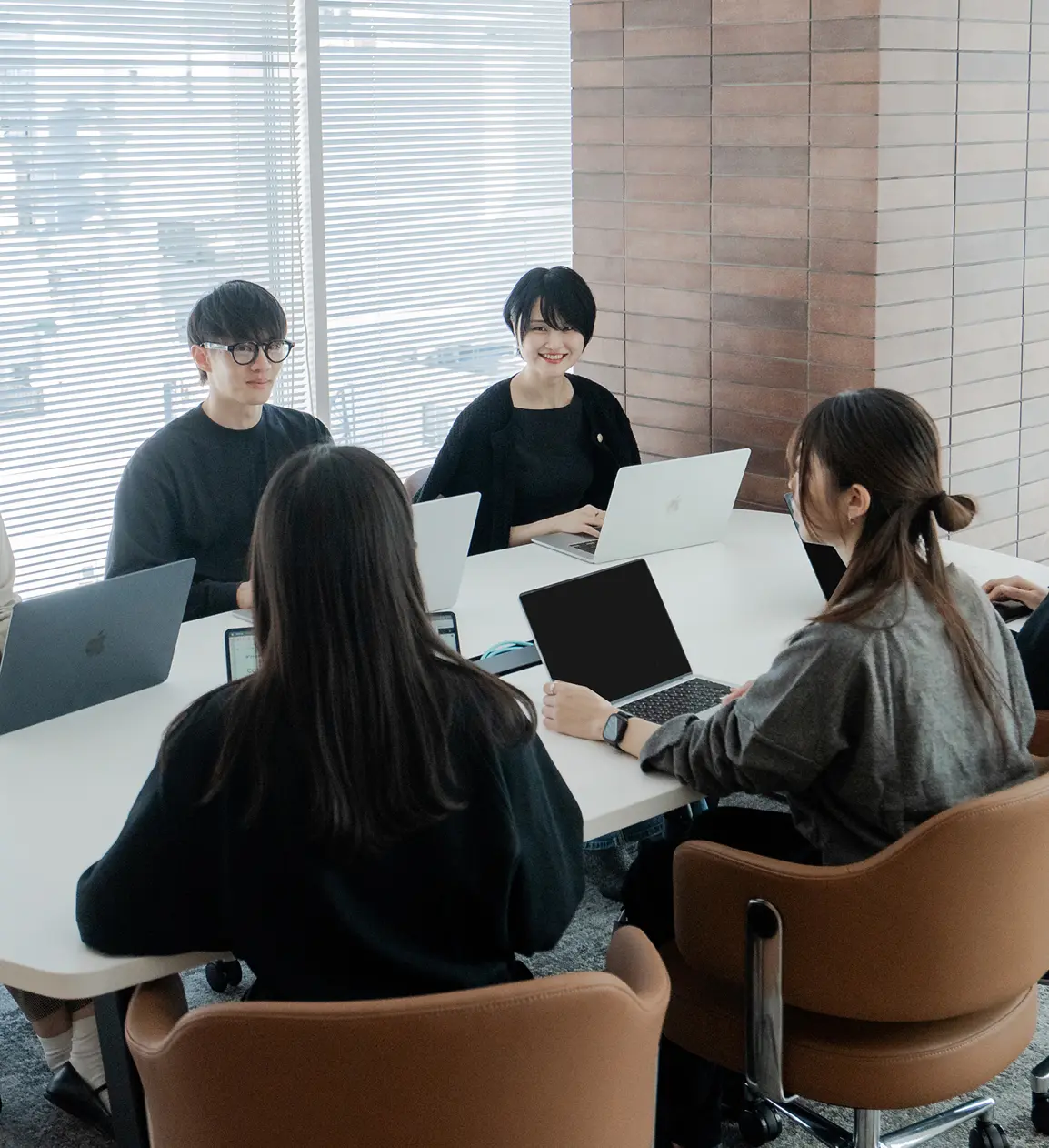 会議室でノートパソコンを使用し、複数人でミーティングを行うマナリンクの社員