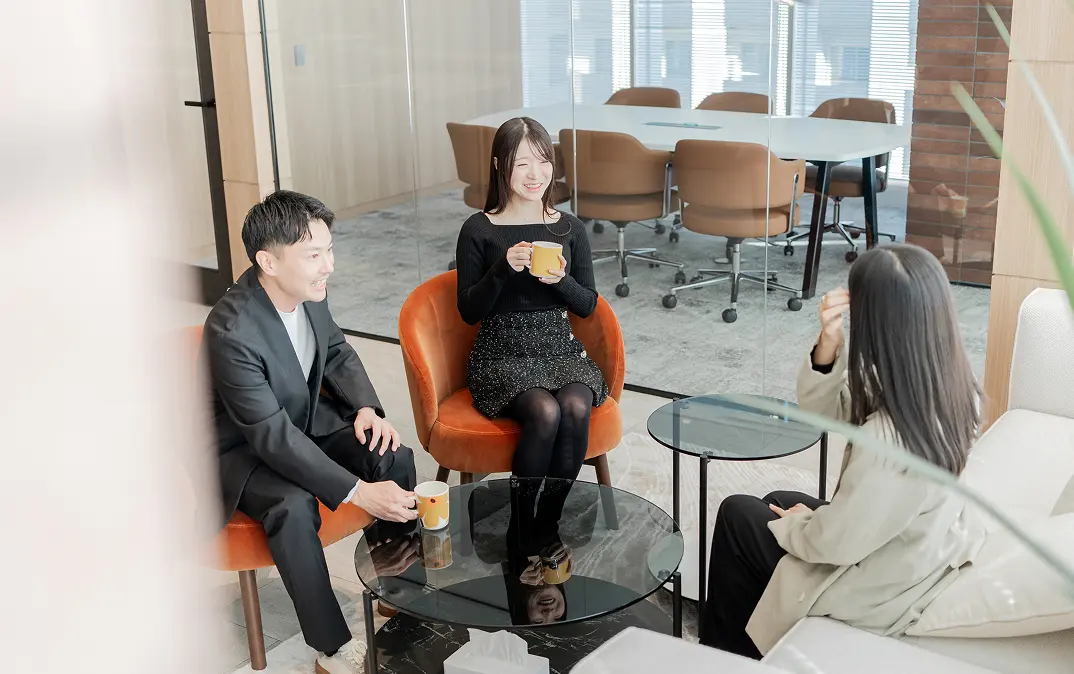 オフィスのラウンジスペースで、コーヒーを飲みながらリラックスして会話するマナリンクの社員